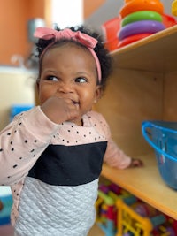 a little girl is playing with toys in a playroom