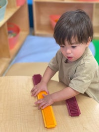 a young boy playing with colorful blocks in a classroom