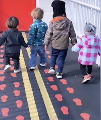 a group of young children walking on a red and black striped path