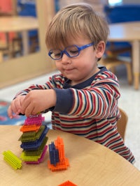 a young boy playing with colorful building blocks in a classroom