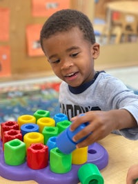 a young boy playing with colorful blocks in a classroom