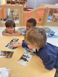 a group of children playing with pictures at a table in a classroom